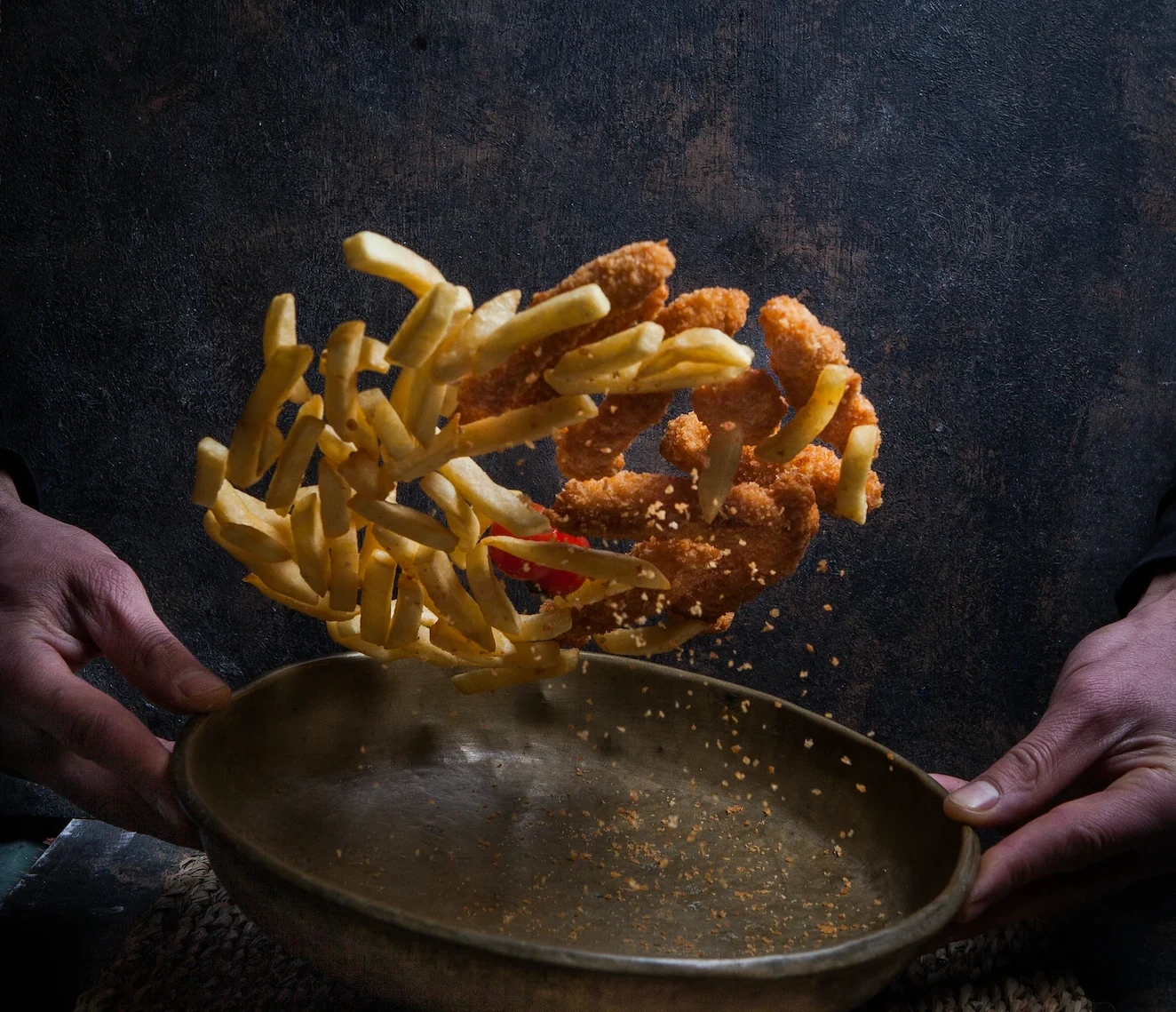 Halal kipproducten en friet die boven een schaal vallen